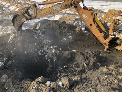 Koparka odkopuje nielegalnie zgromadzone pod ziemią odpady.