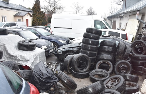 Odpady w postaci opon i innych części samochodowych nielegalnie zgromadzone na otwartym terenie.