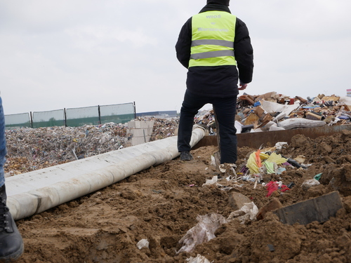 Inspektor Wojewódzkiego Inspektoratu Ochrony Środowiska w Warszawie prowadzi oględziny miejsca nielegalnego gromadzenia odpadów.