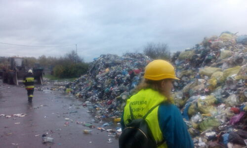 Inspektor Wojewódzkiego Inspektoratu Ochrony Środowiska w Warszawie prowadzi oględziny miejsca wywiezionych z hali odpadów, dogaszonych przez straż.
